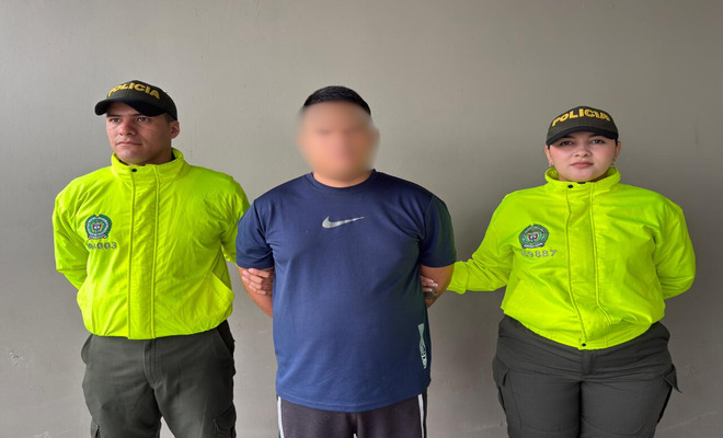 Persona custodiada por dos uniformados de la seccional de investigaci&oacute;n criminal de la Polic&iacute;a Nacional.