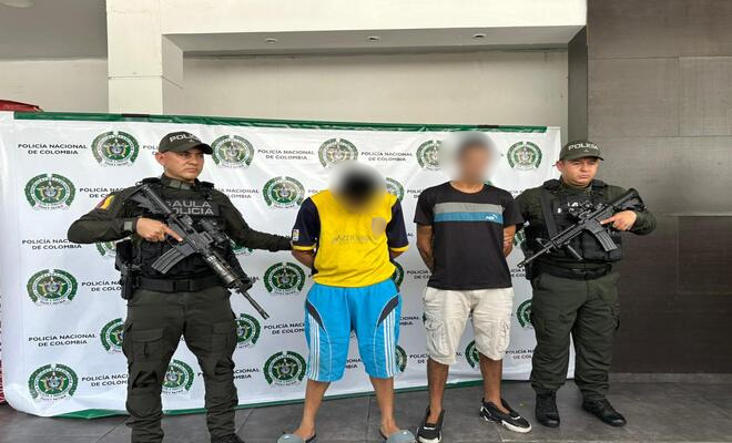 Dos capturados sujetados por dos uniformados de la Policía Nacional
