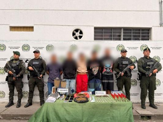cuatro polic&iacute;as, en el medio de ellos cinco hombres capturados con estupefacientes