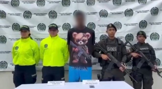 cuatro policías al lado de un hombre capturado con material incautado