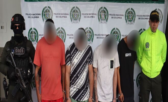 Cuatro personas detenidas son presentadas por dos uniformados de la Policía Nacional de Colombia