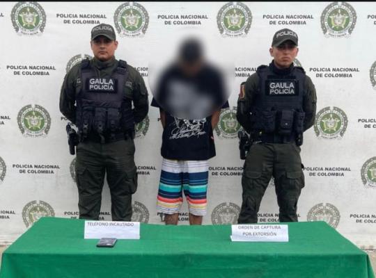 dos polic&iacute;as al lado de un hombre capturado por extorsi&oacute;n