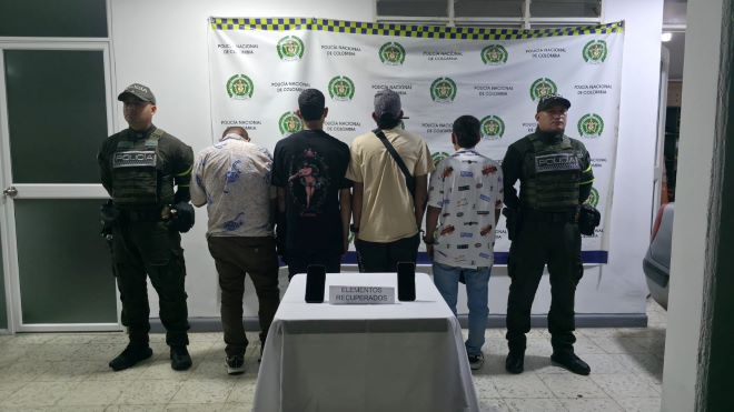 Dos polic&iacute;as al lado de cuatro hombres capturados