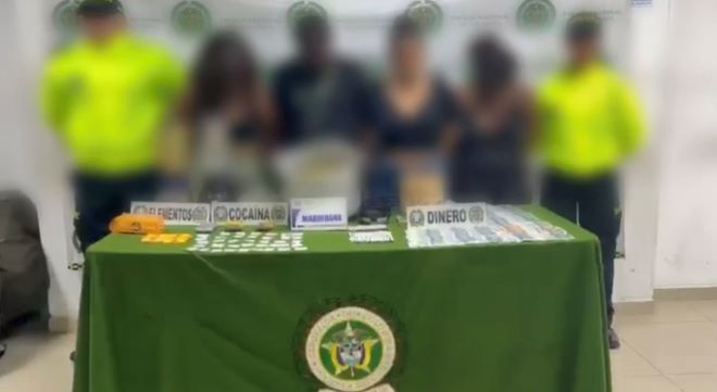 Dos policías al lado de cuatro personas con material incautado