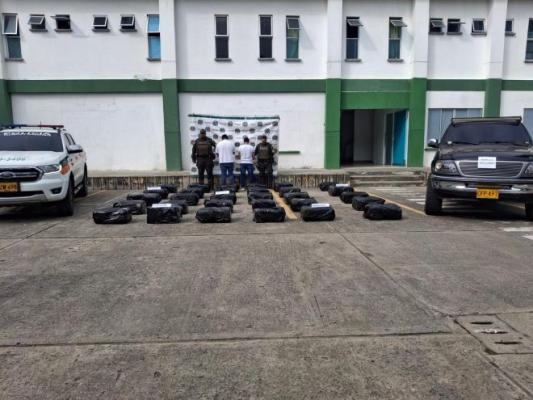 Dos polic&iacute;as al lado de dos hombres capturados