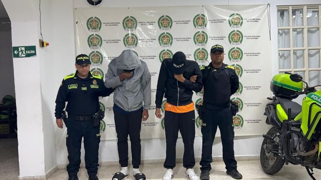 Dos polic&iacute;as al lado de dos hombres capturados