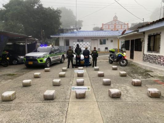 Dos policías, al lado de dos hombres capturados con marihuana y un vehículo incautados