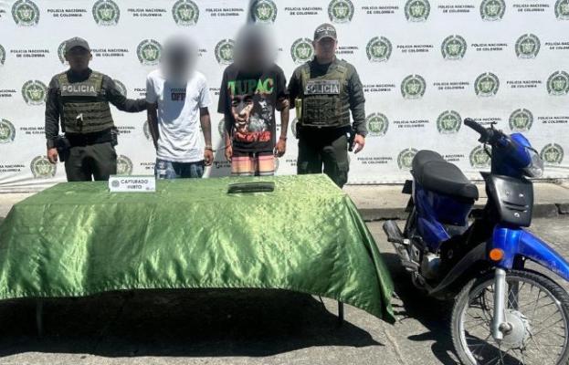 Dos polic&iacute;as al lado de dos hombres capturados por hurto