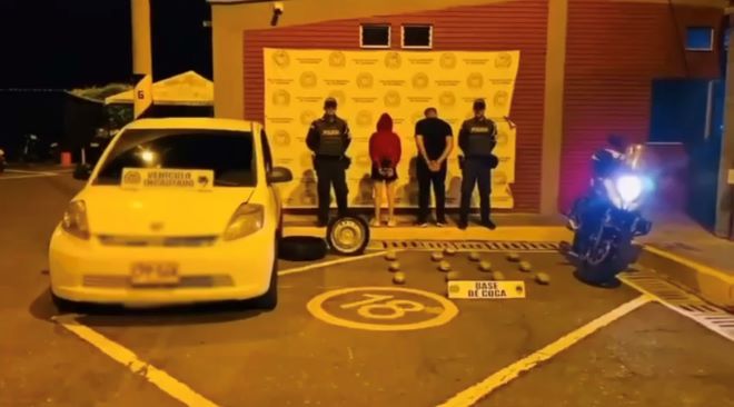 Dos policías al lado de dos personas capturadas con estupefacientes