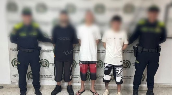 dos policías al lado de tres hombre capturados 