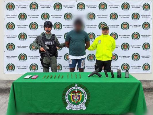 dos policías al lado de un hombre capturado con arma de fuego municiones