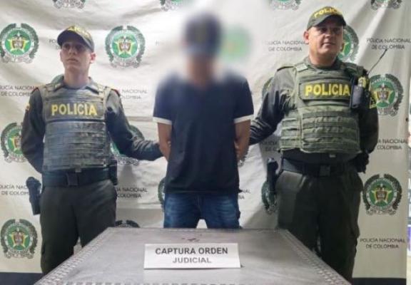 Dos policías al lado de un hombre capturado