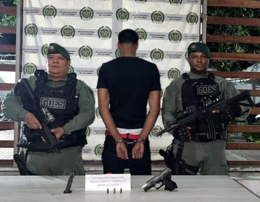 dos policías al lado de un hombre capturado con arma de fuego