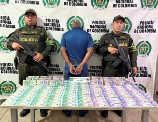 Dos polic&iacute;as en el medio un hombre capturado con dinero