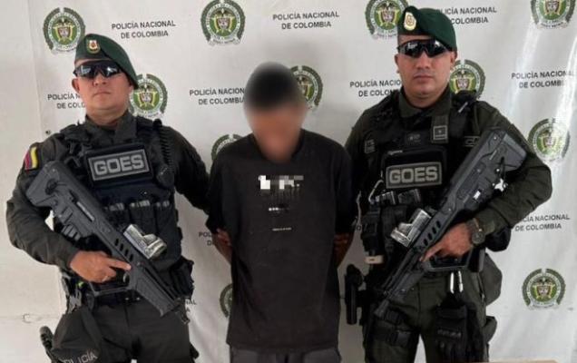 Dos policías al lado de un hombre capturado por orden judicial