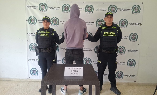 dos policias con un hombre capturado por orden judicial