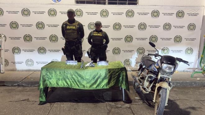 Dos policías con una arma incautada motocicleta