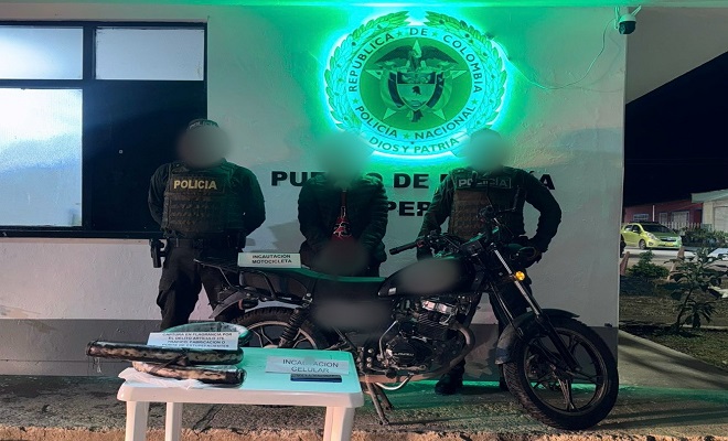 De noche, dos policías junto a una mesa con los elementos incautados, una moto y la persona capturada 
