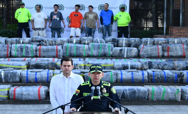 En un escenario al exterior la Polic&iacute;a Nacional de Colombia vocero junto al secretario de seguridad de la  Alcald&iacute;a, detr&aacute;s presentan la incautaci&oacute;n de marihuana envuelta en pl&aacute;sticos.