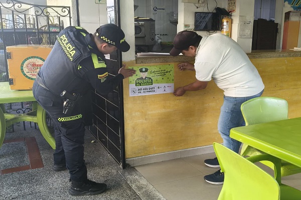 Un Policía y un ciudadano pegando afiche 