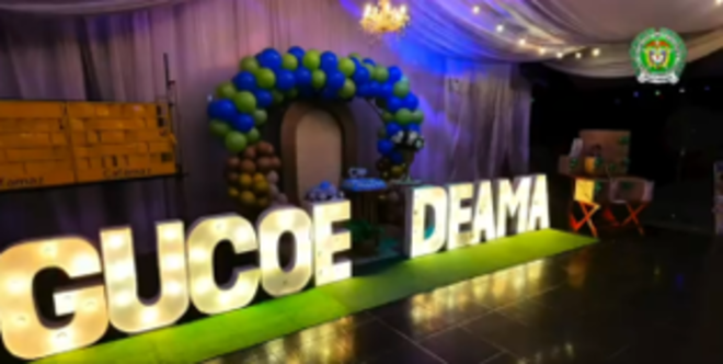 La palabra GUCOE DEAMA en letras grandes con luces amarillas y de fondo bobas decorativas  