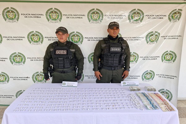 Dos polic&iacute;as junto a una mesa con sustancias estupefacientes y dinero en efectivo incautados