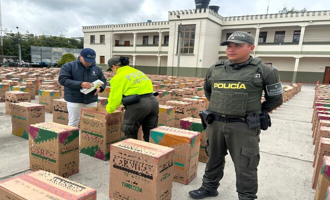 dos Policías revisando incautación de cajas las cuales contienen cigarrillos y un policía custodiando 