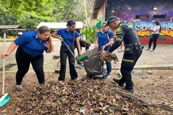 Un uniformado y tres funcionarias de la alcald&iacute;a participan en una jornada de limpieza, recogiendo hojas del suelo en el Malec&oacute;n 