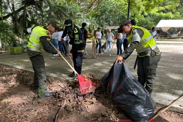 Tres policías realizan labores de barrido y recolección de hojas durante una jornada de ornato