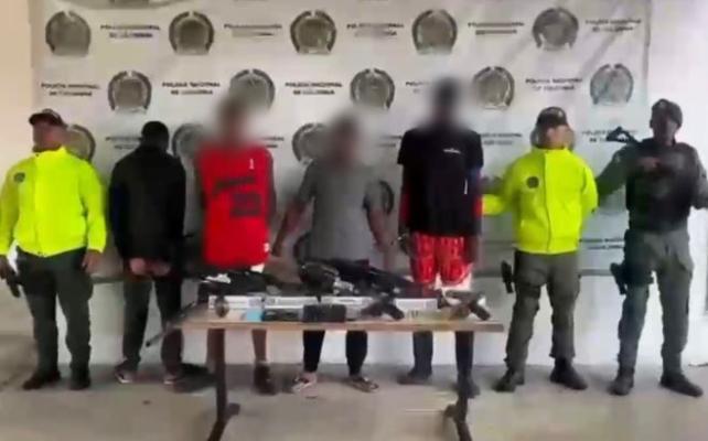 tres policías al lado de cuatro hombres capturados