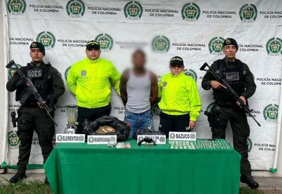 La polic&iacute;a nacional al lado de un hombre capturado con material incautado