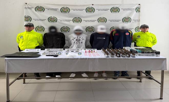 Cuatro personas esposadas capturadas con dos policías en cada lado respectivamente y elementos incautados 