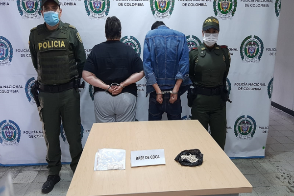 Capturada pareja que transportaba estupefacientes en un carro Personas capturadas-policías custodiando