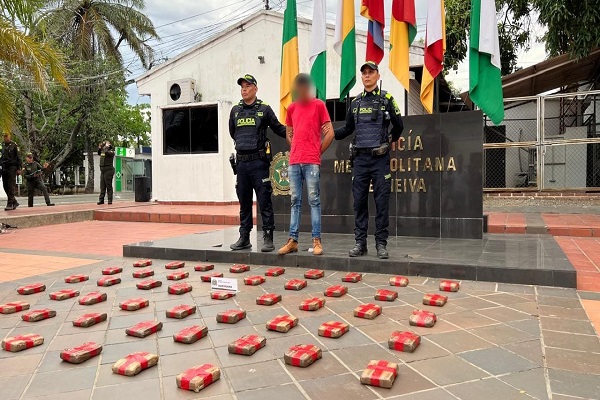 Dos policías junto a un capturado y 50 paquetes de marihuana incautados