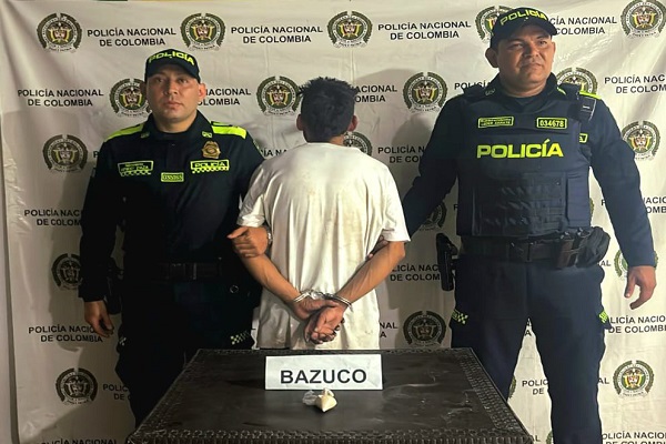 Dos Policías, un capturado, mesa con estupefacientes
