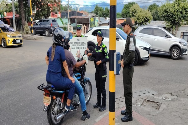 Tres uniformados realizan una campa&ntilde;a preventiva sobre la mendicidad infantil a dos ciudadanos que se movilizan en motocicleta