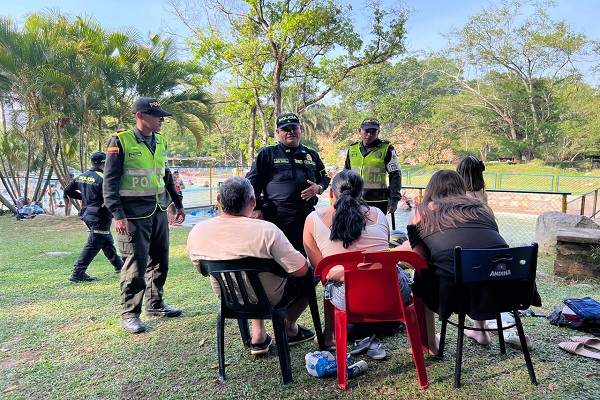 Tres Policías del Grupo de Protección al Turismo y Patrimonio compartiendo recomendaciones a cuatro ciudadanos con el fin de evitar casos de inmersión en niños, niñas y adolescentes 