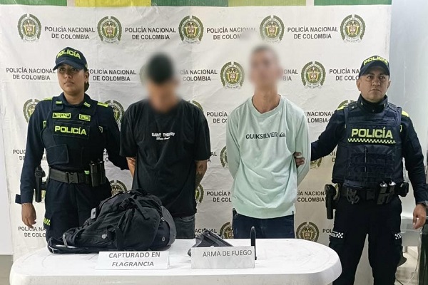 Dos policías custodian a dos hombres capturados