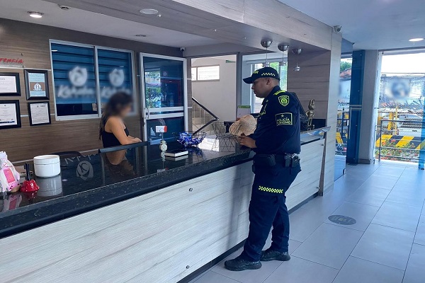 Policía verificando con la ciudadana la verificación la documentación exigida para el funcionamiento del establecimiento