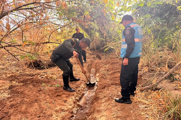 Tres funcionarios remueven arena para formar un canal de agua