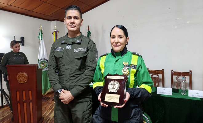 Policía entregando reconocimiento a la coordinadora de la cívica de mayores en su aniversario número 43 