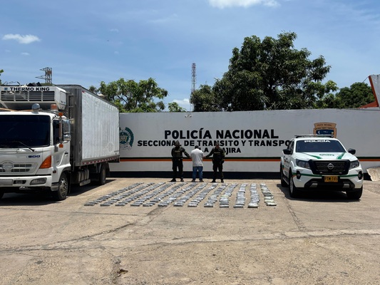 Dos policías, un capturado por el delito de Trafico, fabricación o porte de estupefacientes  a los costados un camión y un vehículo uniformado