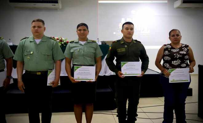 Uniformados y no uniformados, posan con certificados recibidos en una ceremonia.