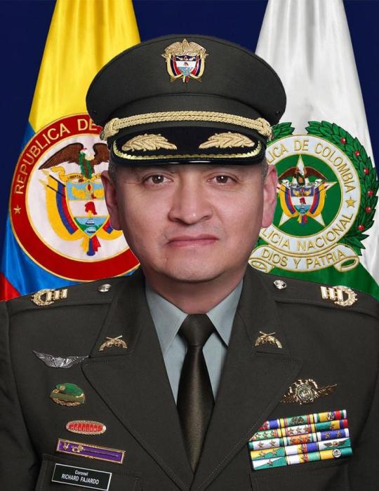 Retrato oficial de una persona con uniforme de la Polic&iacute;a Nacional de Colombia, ubicado frente a las banderas de Colombia y de la instituci&oacute;n; el uniforme incluye insignias, condecoraciones y una gorra de gala, coronel Richard Ra&uacute;l Fajardo Ayala